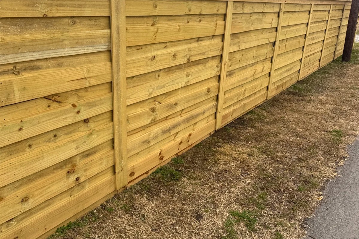 Horizontal cedar fence run along residential street