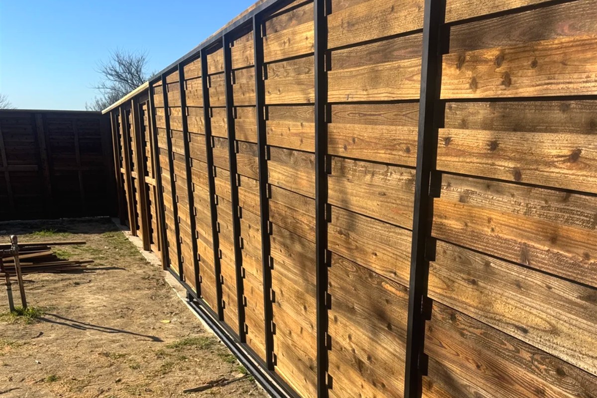 Modern horizontal board fence on steel posts with blue sky